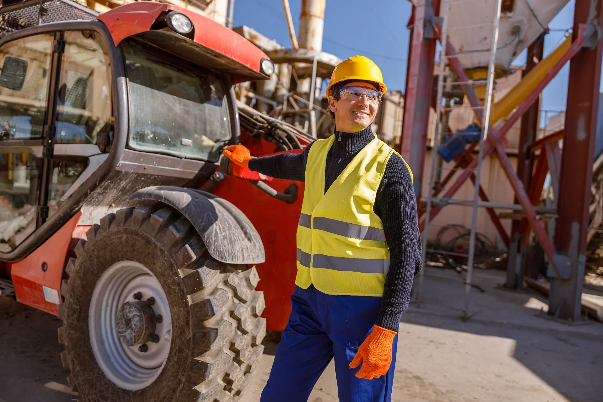 Operator standing next to a telehandler at an industrial plant